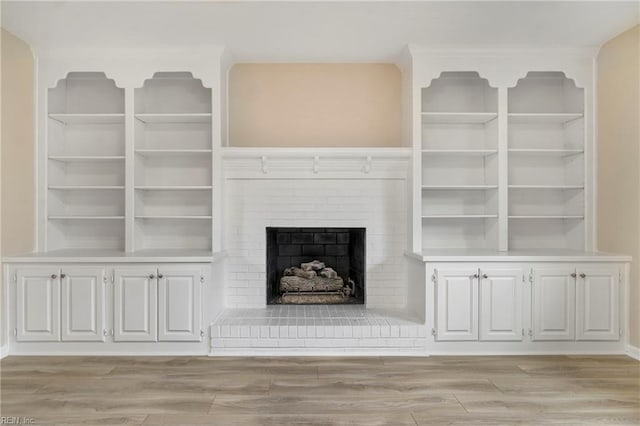 unfurnished living room with a brick fireplace and light wood-style flooring