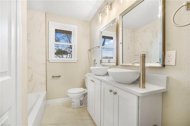 full bath featuring baseboards, double vanity, a sink, toilet, and marble finish floor