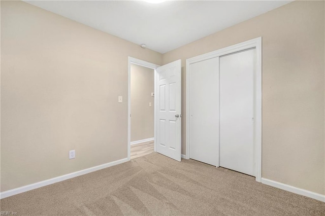 unfurnished bedroom with baseboards, carpet floors, and a closet