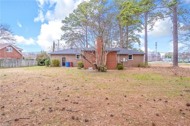 back of property featuring brick siding, a chimney, and fence