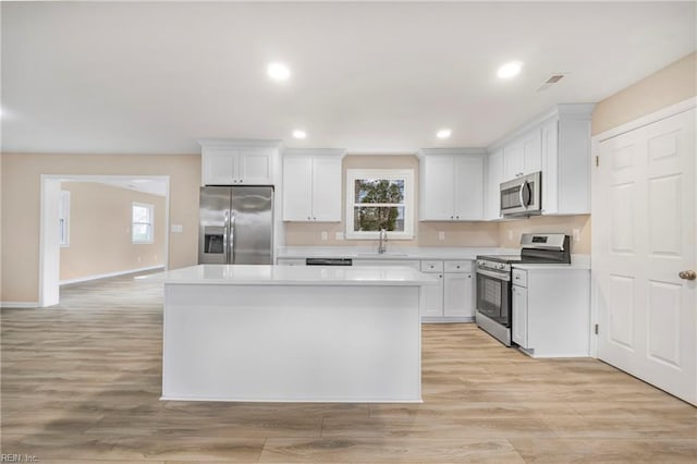 kitchen featuring a sink, appliances with stainless steel finishes, a center island, and light countertops