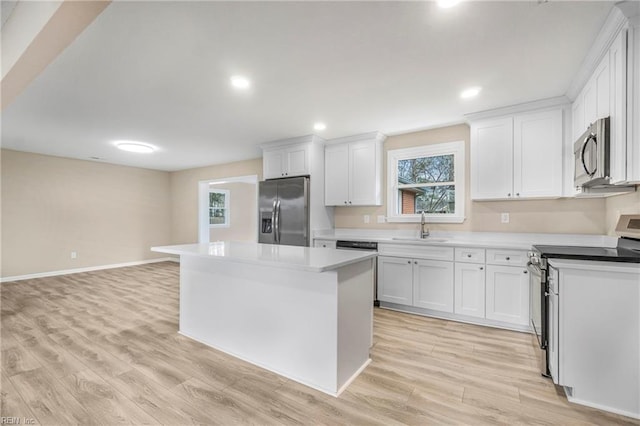 kitchen with a kitchen island, light wood-style flooring, a sink, stainless steel appliances, and white cabinets