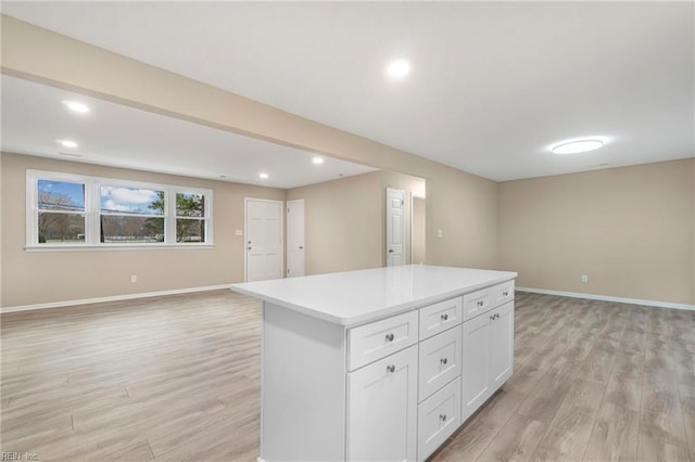 kitchen with baseboards, open floor plan, white cabinetry, light wood-type flooring, and a center island