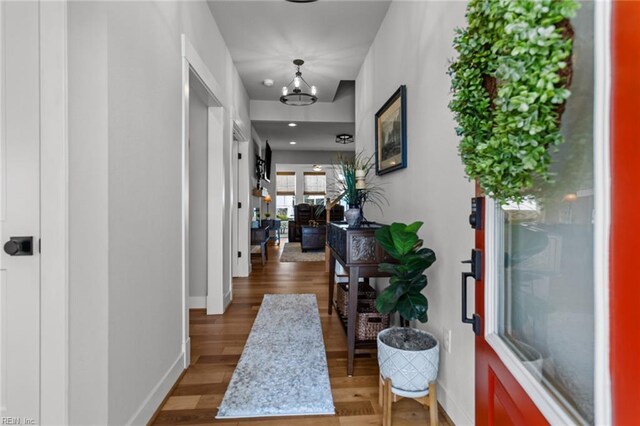 entryway featuring a chandelier, baseboards, and wood finished floors