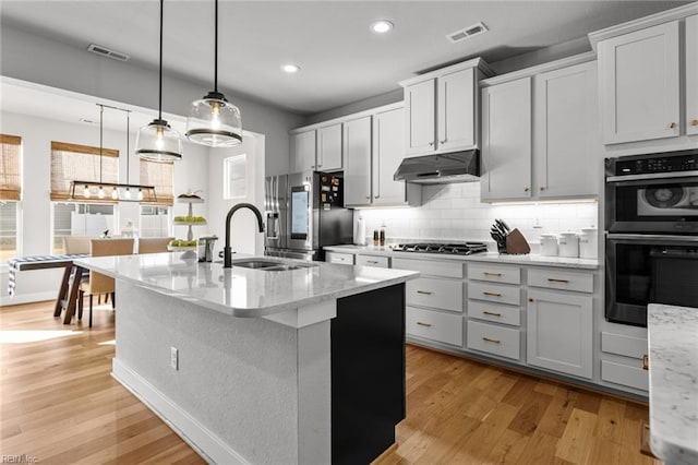 kitchen featuring appliances with stainless steel finishes, visible vents, under cabinet range hood, and a sink