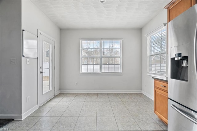 unfurnished dining area featuring light tile patterned floors and baseboards