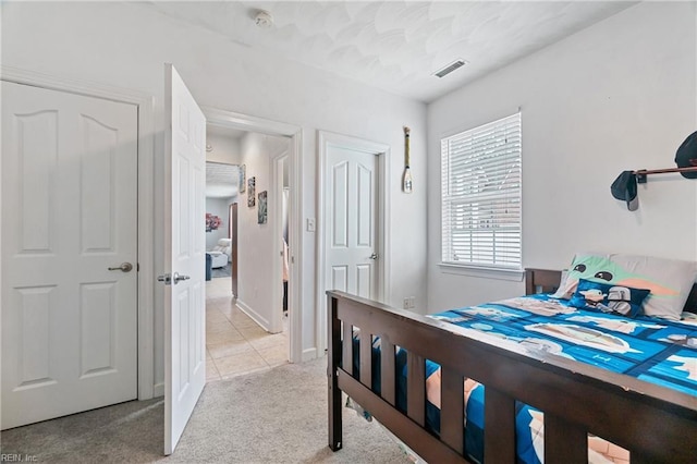 bedroom featuring light carpet, visible vents, and light tile patterned floors