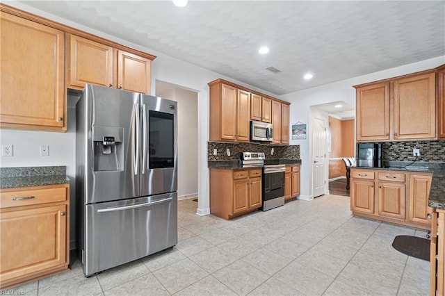 kitchen with dark stone counters, baseboards, tasteful backsplash, and appliances with stainless steel finishes