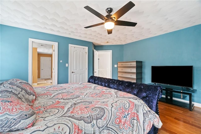 bedroom with ceiling fan, baseboards, and wood finished floors