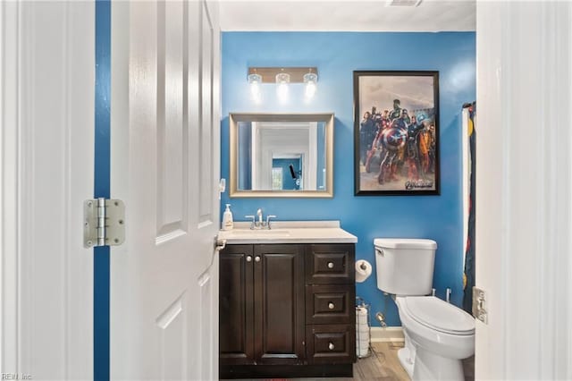 bathroom featuring vanity, toilet, wood finished floors, and baseboards