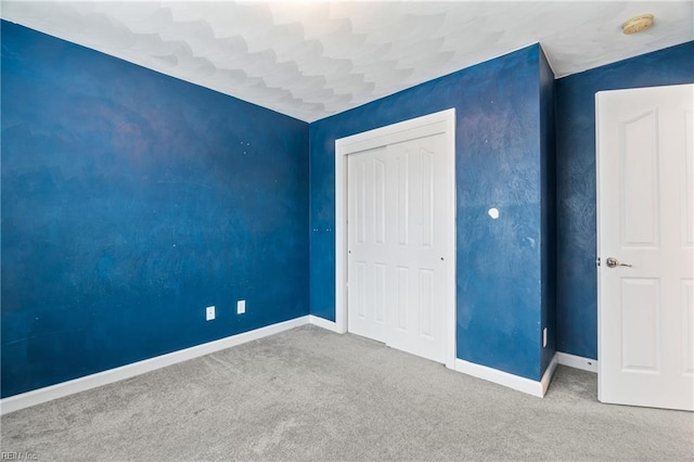 unfurnished bedroom with a closet, carpet flooring, and baseboards