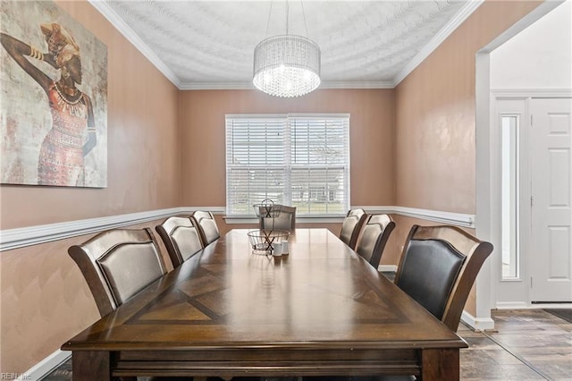 dining space with an inviting chandelier, wood finished floors, crown molding, and baseboards