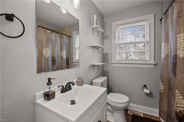 bathroom featuring visible vents, baseboards, toilet, wood finished floors, and vanity