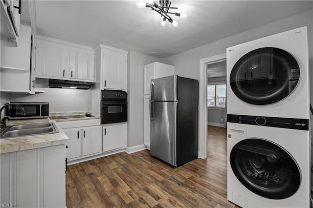 kitchen with stacked washer / dryer, black appliances, under cabinet range hood, white cabinetry, and a sink