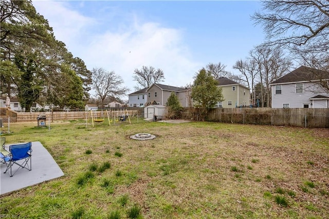 view of yard featuring a residential view, an outdoor fire pit, a fenced backyard, an outdoor structure, and a patio