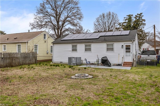 rear view of property with an outdoor fire pit, solar panels, a fenced backyard, entry steps, and a lawn