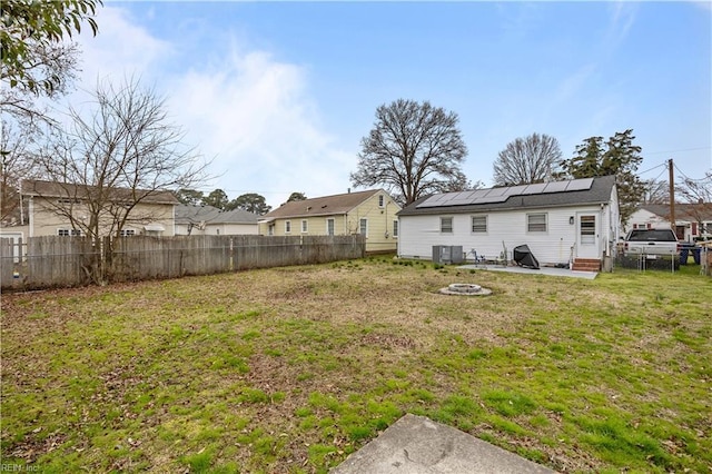 view of yard featuring entry steps, a fenced backyard, central AC, and a fire pit