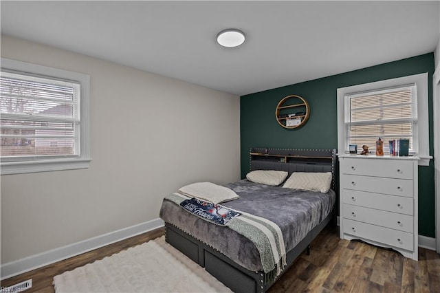 bedroom with visible vents, wood finished floors, and baseboards