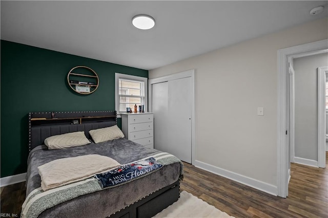 bedroom with dark wood-style floors, a closet, and baseboards