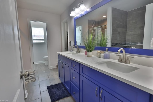 full bathroom with double vanity, tiled shower, toilet, and a sink