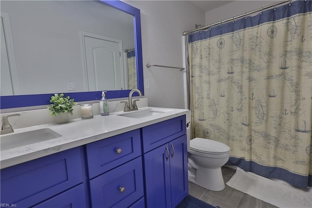 full bath featuring double vanity, toilet, a textured wall, and a sink