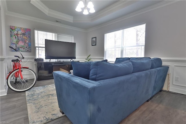 living room featuring a tray ceiling, a notable chandelier, wood finished floors, and wainscoting