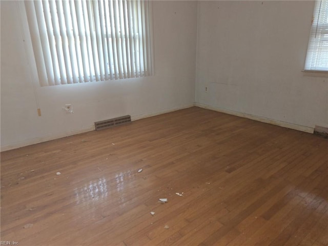 spare room with a healthy amount of sunlight, visible vents, and wood-type flooring