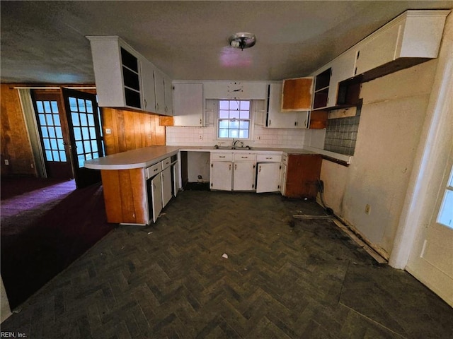 kitchen featuring open shelves, a peninsula, backsplash, and a sink