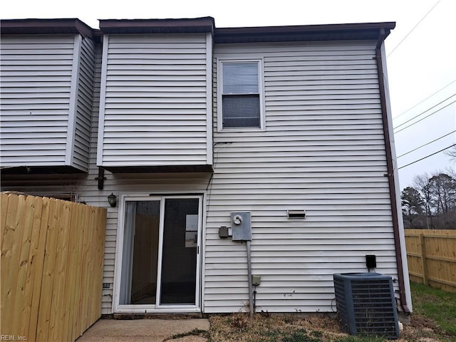 rear view of property featuring central air condition unit and fence