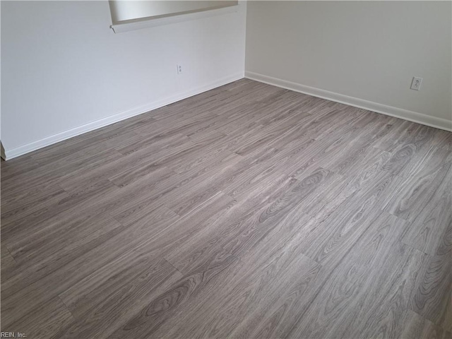 unfurnished room with baseboards and dark wood-style flooring