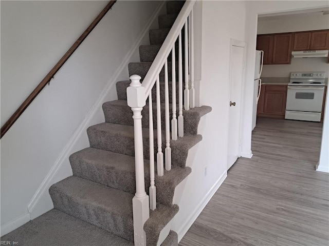 stairway with wood finished floors and baseboards