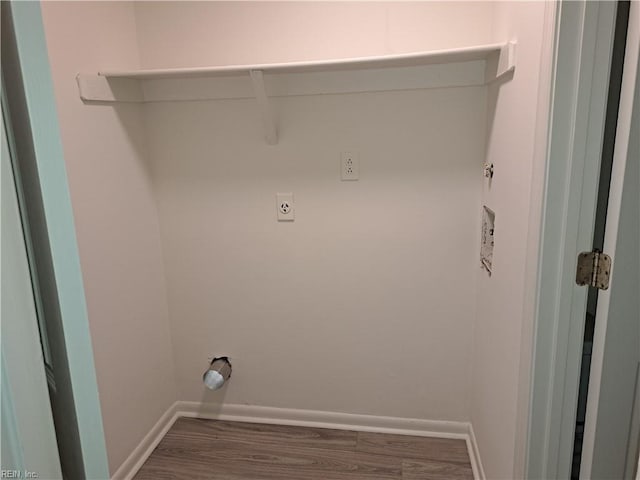 laundry area with electric dryer hookup, baseboards, wood finished floors, and laundry area