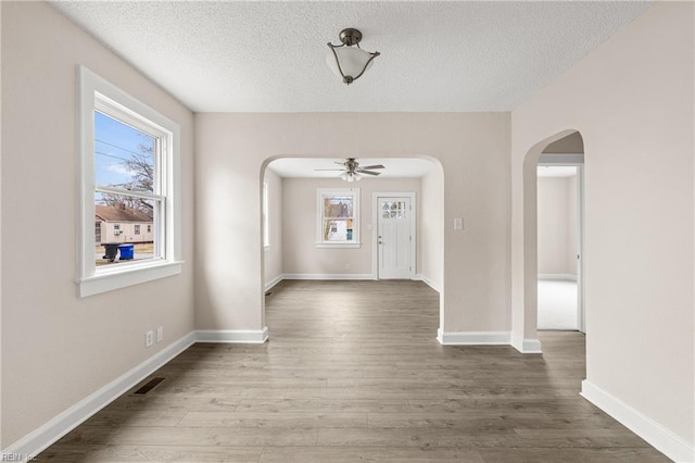 interior space featuring wood finished floors, visible vents, arched walkways, and a textured ceiling