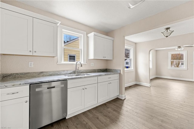 kitchen featuring a healthy amount of sunlight, wood finished floors, white cabinetry, a sink, and dishwasher