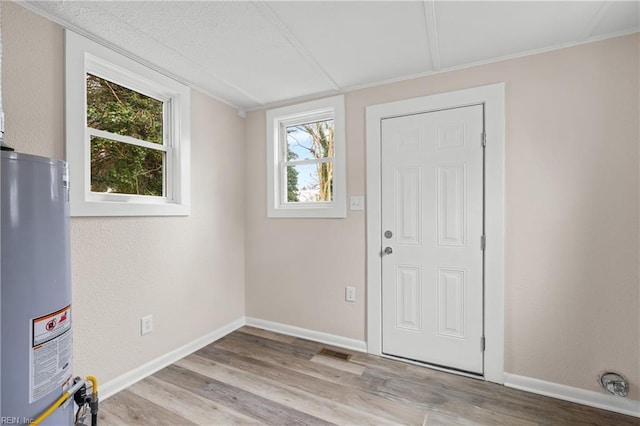 entryway featuring gas water heater, wood finished floors, baseboards, and visible vents