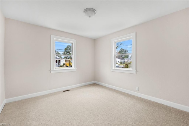 empty room with visible vents, baseboards, and light colored carpet