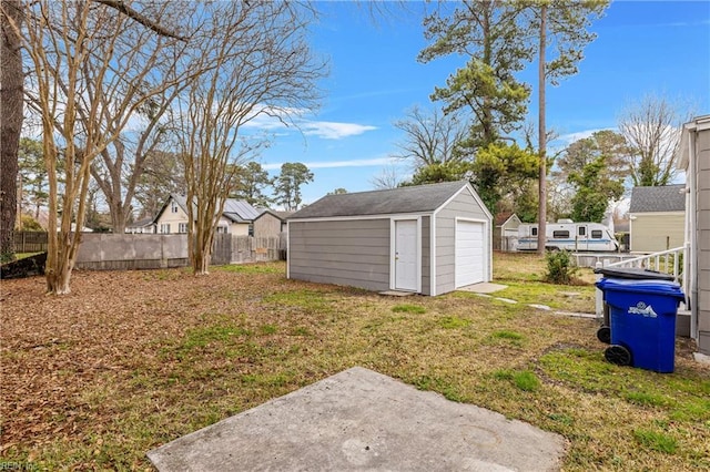 view of yard featuring a residential view, a detached garage, an outdoor structure, and fence