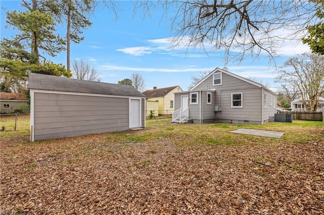 back of property with crawl space, a yard, an outdoor structure, and fence