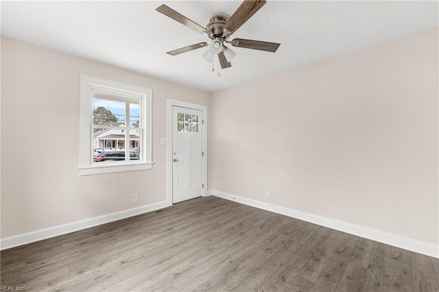 unfurnished room with wood finished floors, baseboards, and ceiling fan