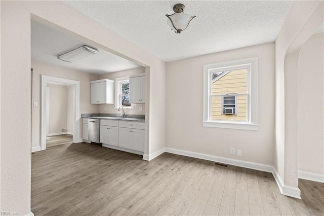 unfurnished dining area featuring a sink, baseboards, light wood-style floors, and a textured ceiling