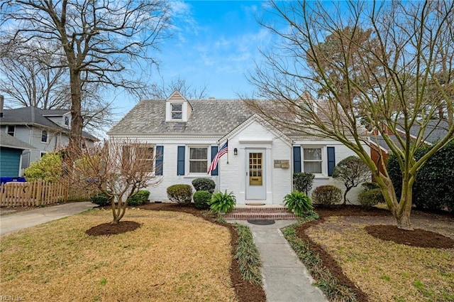 cape cod home with brick siding, a front lawn, and fence