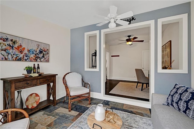 living room with baseboards and a ceiling fan