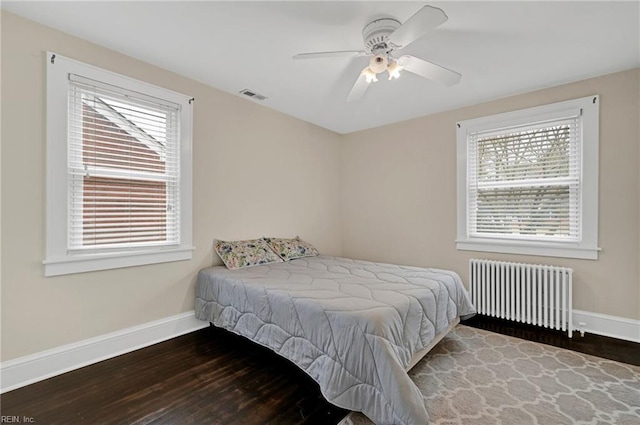 bedroom featuring visible vents, baseboards, radiator heating unit, wood finished floors, and a ceiling fan