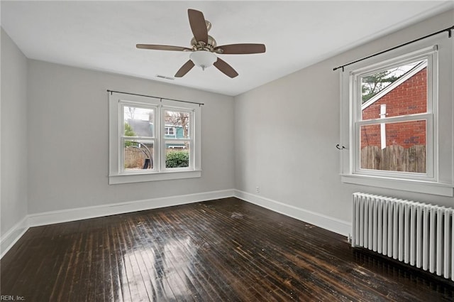 spare room featuring baseboards, radiator, ceiling fan, and hardwood / wood-style flooring