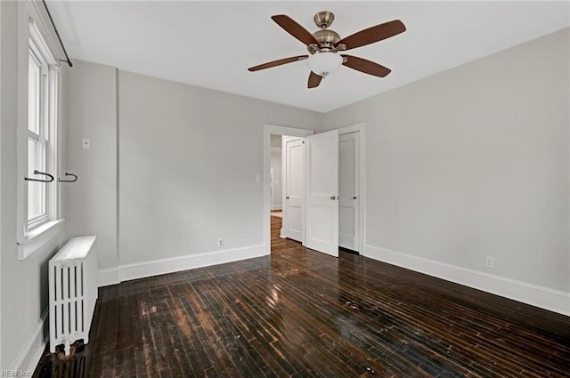 unfurnished bedroom with radiator, a ceiling fan, baseboards, and hardwood / wood-style flooring