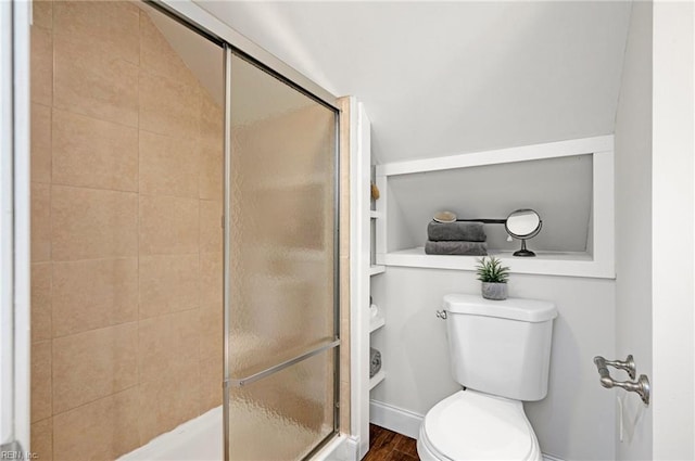 bathroom with a shower stall, toilet, and wood finished floors