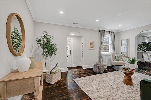 living room with arched walkways, wood finished floors, baseboards, and ornamental molding