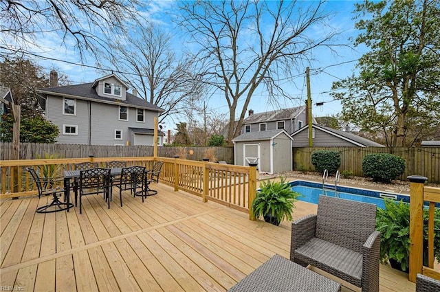 wooden terrace with a storage unit, a fenced in pool, an outbuilding, and a fenced backyard