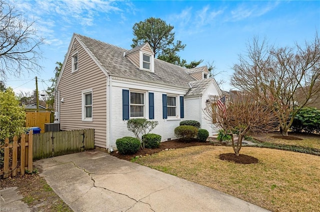 view of front facade with brick siding, a front yard, and fence