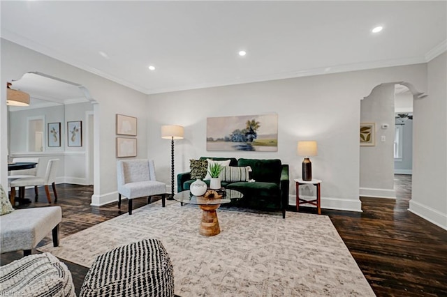 living area featuring dark wood-type flooring, ornamental molding, recessed lighting, arched walkways, and baseboards